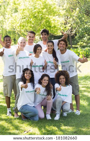 Group portrait of confident volunteers showing thumbs up in park