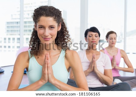 Portrait of sporty young women with joined hands at a bright fitness studio