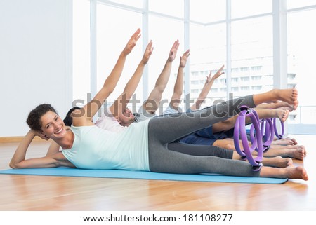 Full length of fitness class stretching legs and hands in row at yoga class