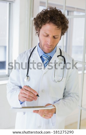 Serious handsome male doctor writing reports in the hospital