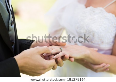 Closeup of groom placing ring on brides finger on their wedding day