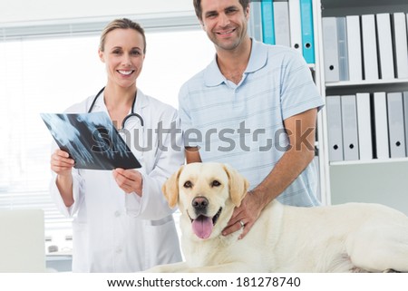 Portrait of happy pet owner and veterinarian with Xray of dog in hospital