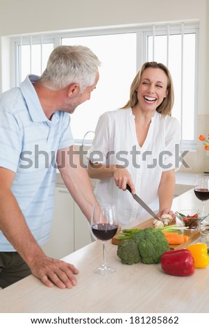Laughing couple making dinner together at home in the kitchen