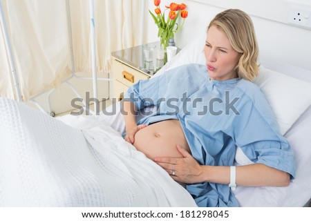High angle view of expectant woman suffering from labor pains in hospital ward