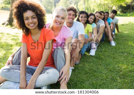 Portrait of confident multiethnic friends sitting in a line on campus