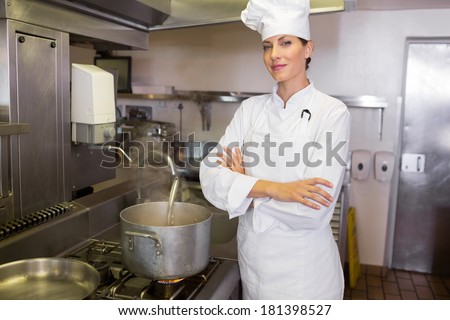 Portrait of a smiling female cook with arms crossed standing in the kitchen
