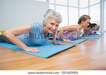 Fitness group doing cobra pose in row at the yoga class