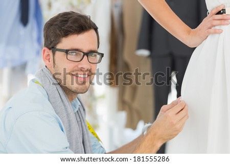 Closeup of a male fashion designer adjusting dress on model in the studio