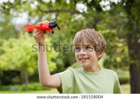 Excited young boy playing with a toy plane at the park