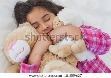 Close-up of a young girl sleeping with stuffed toys in bed at home