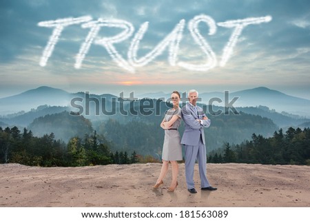 The word trust and serious businessman standing back to back with a woman against scenic countryside with mountains