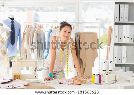 Portrait of a beautiful female fashion designer with rack of clothes in the store