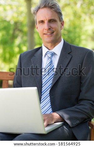 Thoughtful businessman with laptop sitting on park bench