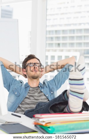 Relaxed casual young man with legs on desk in a bright office