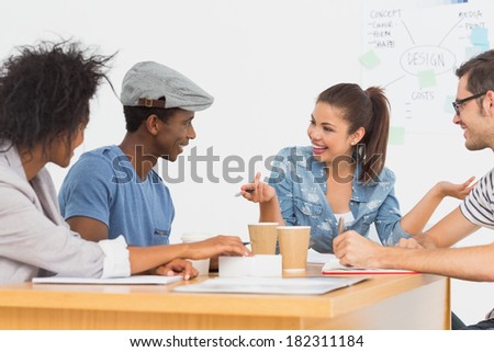 Group of happy artists in discussion at desk at the office