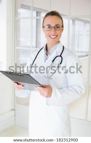 Portrait of a happy beautiful female doctor with clipboard standing in the hospital
