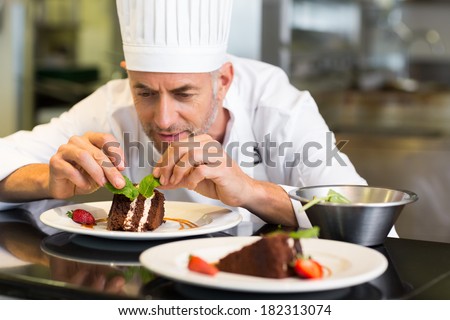Closeup of a concentrated male pastry chef decorating dessert in the kitchen