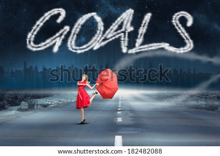 The word goals and beautiful woman posing with a broken umbrella against road leading out to the horizon