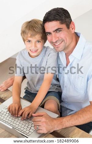 High angle portrait of happy father and son using laptop at table in house