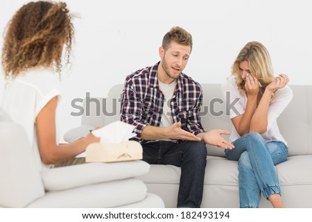 Man speaking to therapist at couples therapy while woman is crying at therapy session