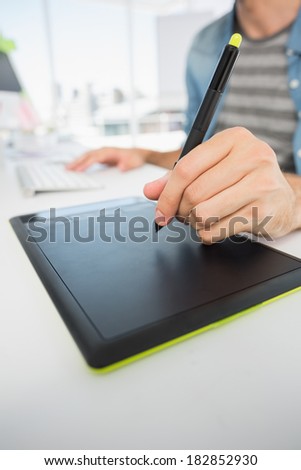 Closeup mid section of a casual male photo editor using graphics tablet in a bright office