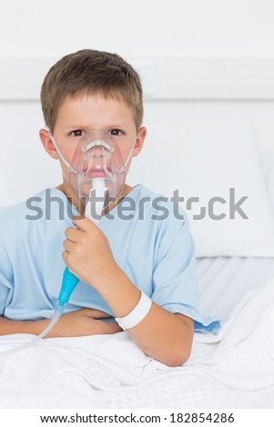 Portrait of little boy wearing oxygen mask in hospital ward