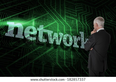 The word network and thoughtful businessman standing back to camera against green and black circuit board