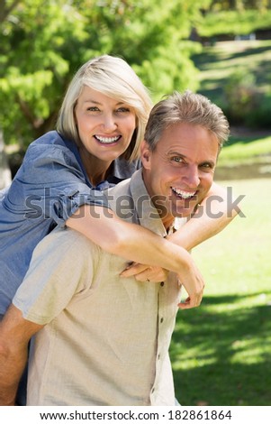Portrait of happy man giving piggyback ride to woman in park