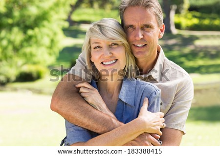 Portrait of loving man embracing woman from behind in park