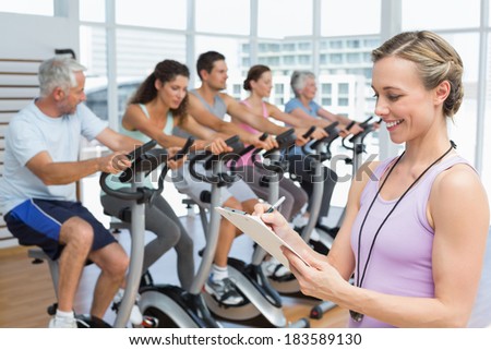 Portrait of a trainer with people working out at bike class in gym