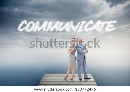 The word communicate and serious businessman standing back to back with a woman against cloudy sky over ocean