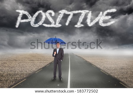 The word positive and businessman smiling at camera and holding blue umbrella against misty brown landscape with street