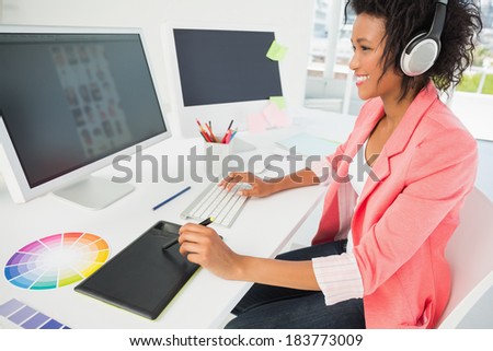 Side view of a casual female photo editor using computer in a bright office