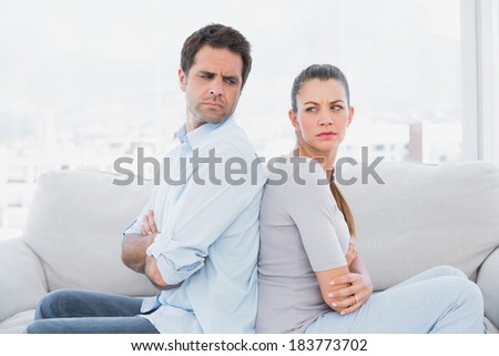 Angry couple sitting back to back on the couch at home in the living room