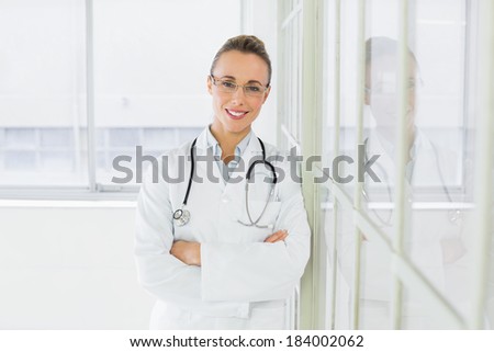 Portrait of a beautiful happy female doctor standing with arms crossed in the hospital