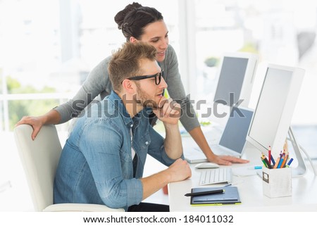 Team of designers looking at the computer in creative office