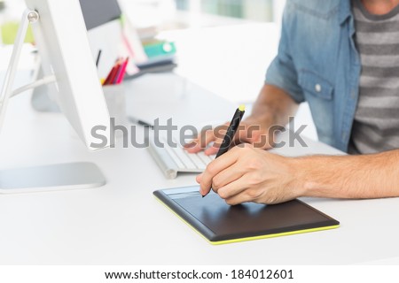 Closeup mid section of a casual male photo editor using graphics tablet in a bright office