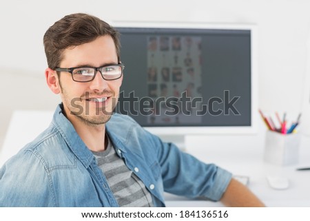 Portrait of a casual male photo editor in front of computer at office