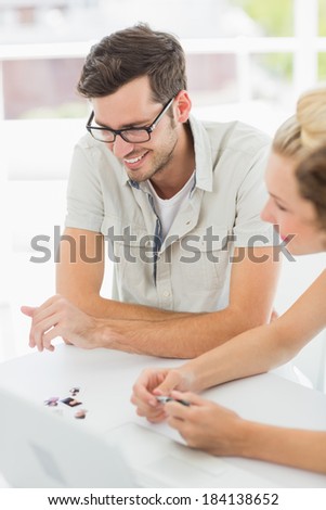 Closeup of a smiling young man and woman working at desk in a bright office