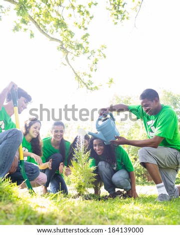 Group of environmentalists watering plant in park