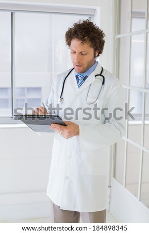 Serious handsome male doctor writing reports in the hospital