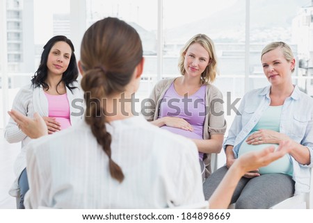 Pregnant women listening to gesturing doctor at antenatal class at the hospital