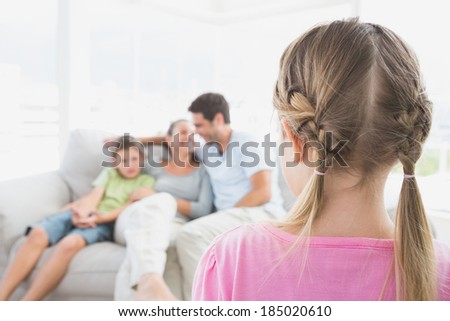 Little girl watching her family on the couch at home in the living room