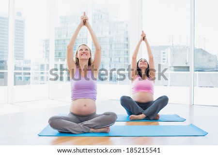 Happy pregnant women in yoga class sitting in lotus pose in a fitness studio