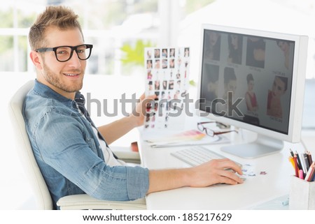 Handsome editor working at his computer smiling at camera in creative office