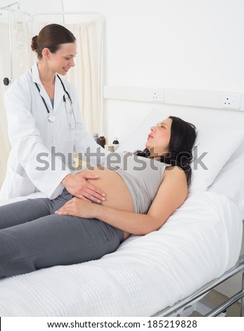 Happy female doctor talking with pregnant woman in examination room at hospital