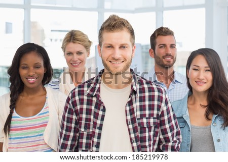 Diverse design team standing and smiling at camera in creative office