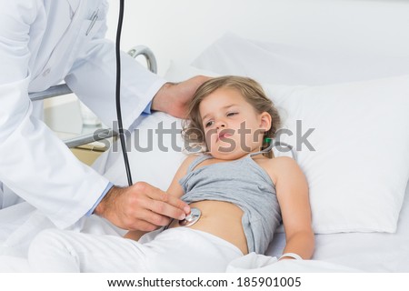 Midsection of doctor checking stomach of sick girl in hospital ward