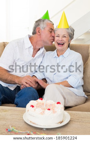 Senior couple sitting on couch celebrating a birthday at home in living room