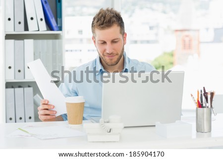 Happy man working at his desk on laptop in creative office